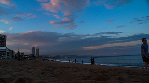 People on beach against sky during sunset
