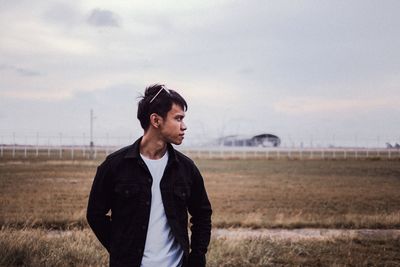 Man looking away while standing on land against sky