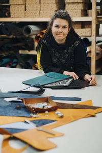 Tailoring eco leather laptop cases. woman designer posing with eco leather textile product at her