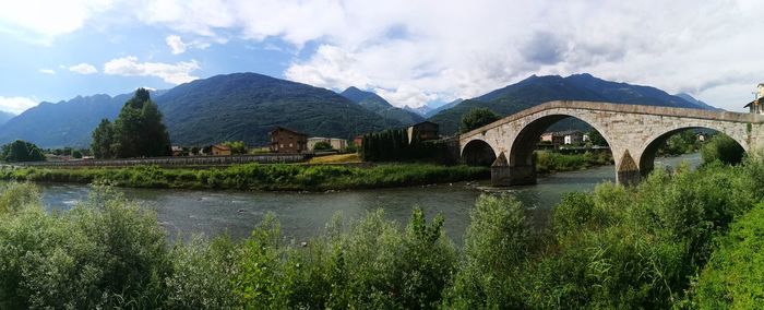 Arch bridge over river against sky