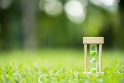 Close-up of wooden hourglass on grassy field