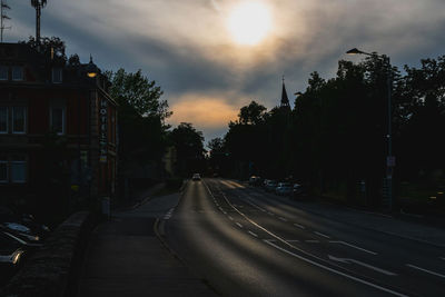 Road amidst trees against sky during sunset