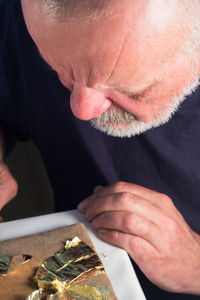 Craftsperson looking at gold leaf on table