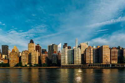 River by buildings against blue sky