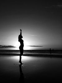 Silhouette woman standing on beach against sky during sunset