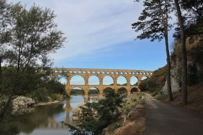 Arch bridge over river against sky