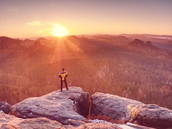 Man enjoy sunny nisty morning above misty valley. fantastic dreamy sunrise on top of rocky mountain