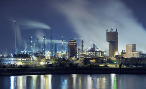 Illuminated petrochemical industry factory by a river at night