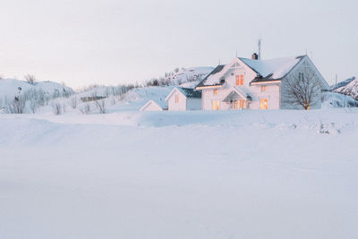 Houses on snow covered land against sky