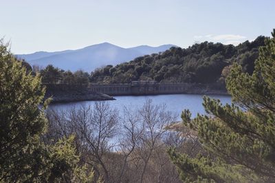 Scenic view of river by mountains against clear sky