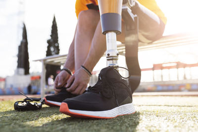 Hands of athlete tying shoelace on sunny day