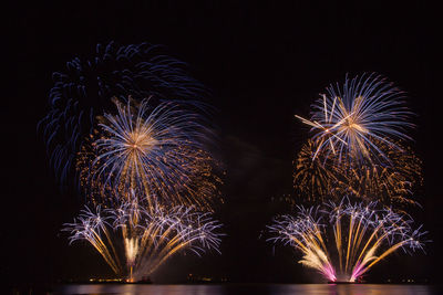 Low angle view of firework display over river at night