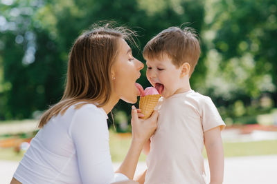 Young caucasian mother with a little boy eating ice cream outdoors. summer food and free time
