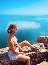 Rear view of woman sitting on the upper rock of gibraltar. 