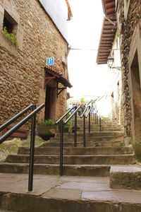 Staircase hanging by building against sky