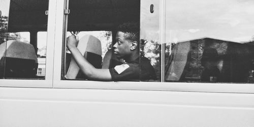 Portrait of young man sitting in glass window