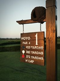 Close-up of information sign on tree against sky