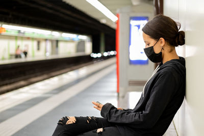 Side view of woman sitting at railroad station