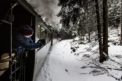 Man walking on snow covered plants during winter