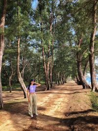 Rear view of man standing on footpath amidst trees in forest