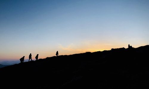 Silhouette people on mountain against clear sky during sunset