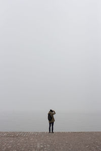 Rear view of man standing on sea against sky