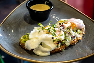 A slice of avocado toast topped with poached eggs and hollandaise sauce.