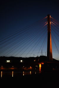 Low angle view of suspension bridge against sky at night