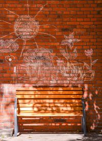 Wooden bench in front of brick wall with chalk drawings