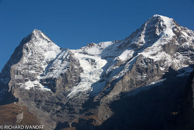 Scenic view of snowcapped mountains against clear blue sky