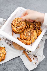 Female hand taking a fresh cinnamon bun from the dish.