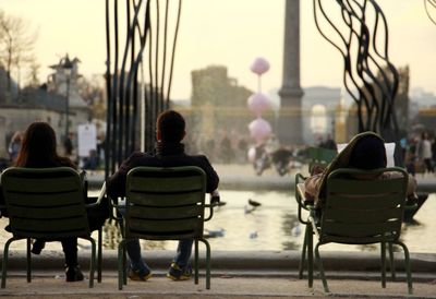 Rear view of people sitting on chair in city