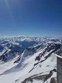 Aerial view of snowcapped mountains against clear blue sky