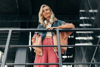 Portrait of young woman standing against railing