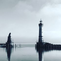 Lighthouse by sea against sky