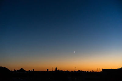 Silhouette cityscape against clear sky during sunset