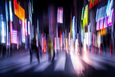 Blurred motion of city street amidst illuminated buildings at night