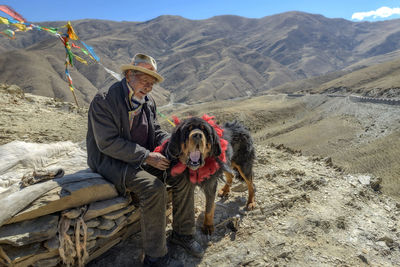 Man sitting with dog on mountain