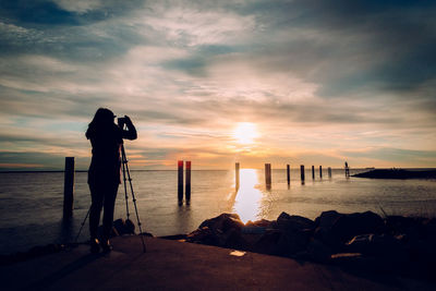 Full length of woman photographing sea during sunset