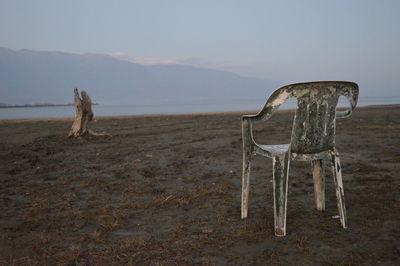 Chair on beach against clear sky