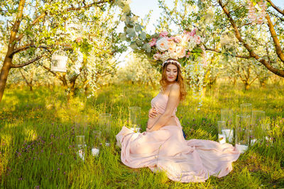 Woman standing by flowering plants against trees