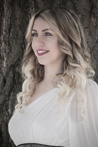 Smiling young woman looking away while standing on snow covered field