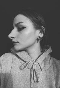 Close-up portrait of young woman against black background