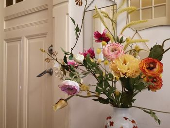 Close-up of pink flowers in vase against wall at home