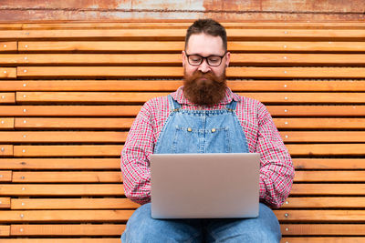 Focused bearded hipster man freelancer using laptop, writing email or message, chatting, shopping.