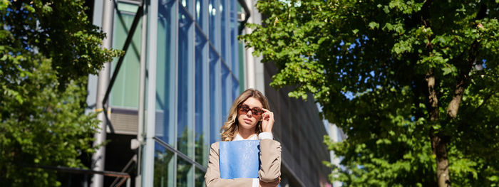 Young woman standing against trees