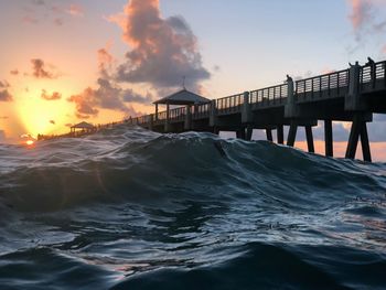 Pier over sea against sky during sunset