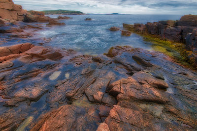 Rock formation on sea shore against sky