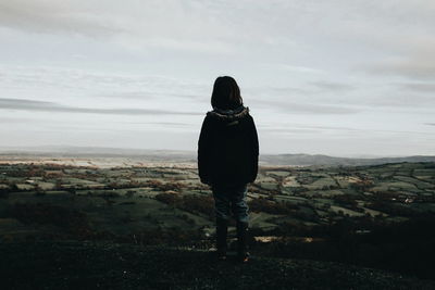 Rear view of woman standing on landscape against sky