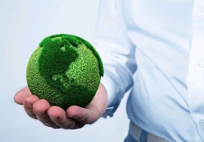 Midsection of man holding green spherical ball against white background